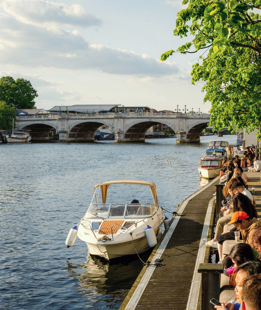 people standing by the river, in which we see docked boats